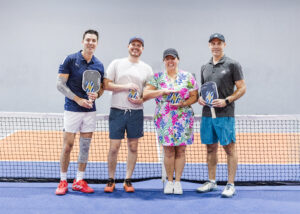 4 pickleballers posing in front of the net