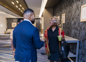 2 FLAGGL 2025 Conference attendees greeting each other with a handshake