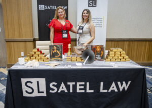 2 sponsors for Satel Law at the 2025 FLAGGL conference, posing for a photo at their booth